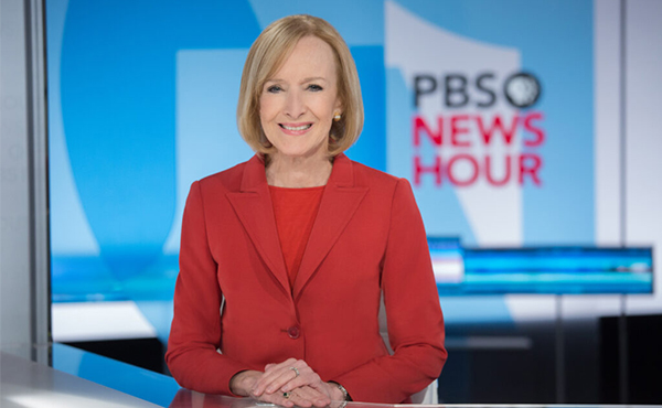 Judy Woodruff seated at PBS NewsHour desk