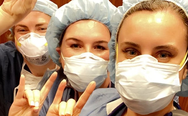 Nicole Prodan ‘16 with Katherine DeStefano ’16 and Nicolette Tiernan ‘16 posing with 'Stags Up' in scrubs (including masks) for the camera in the North Shore University Hospital
