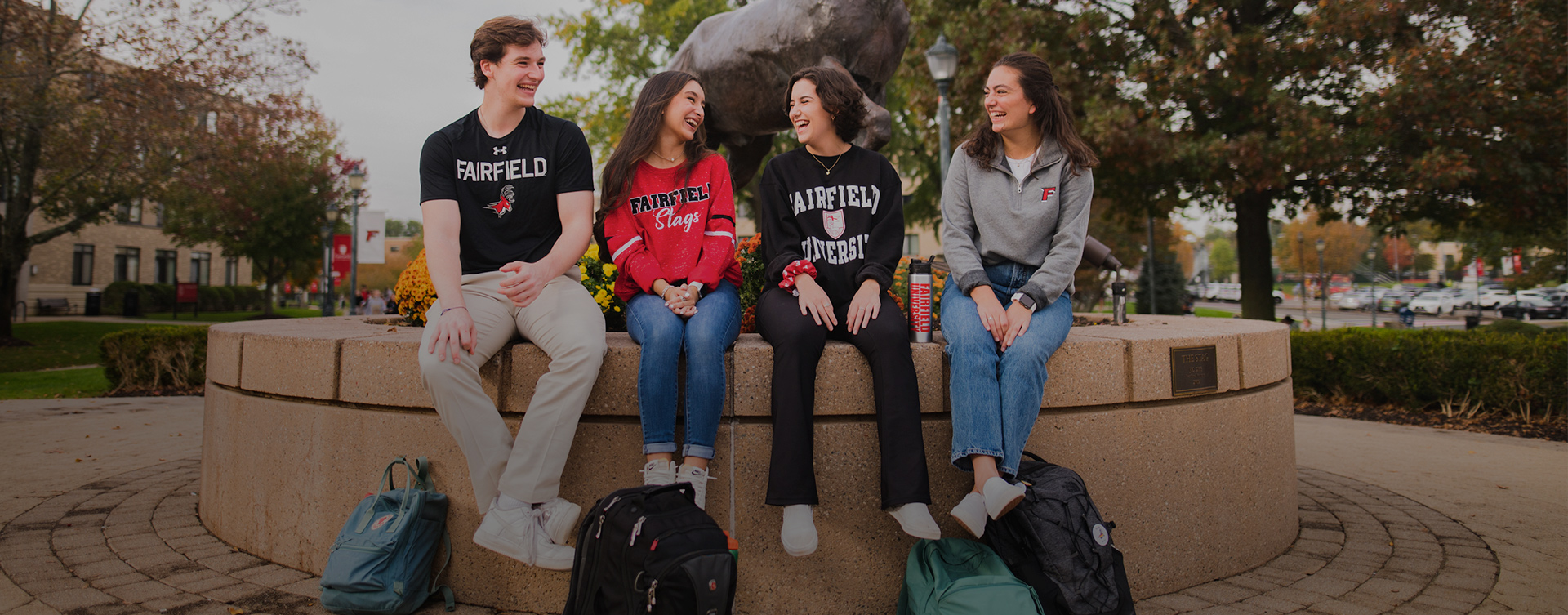 Four Fairfield Students sitting and talking in front of Stag Statue.